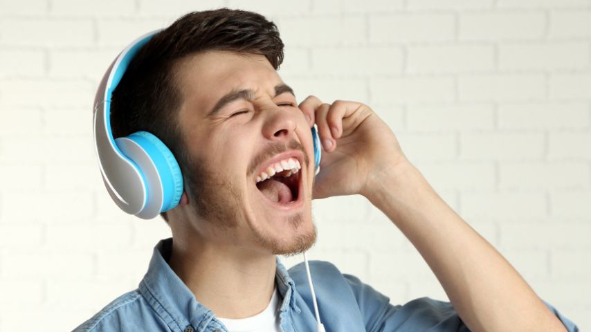 Młody mężczyzna słuchający muzyki przez nauszne słuchawki.