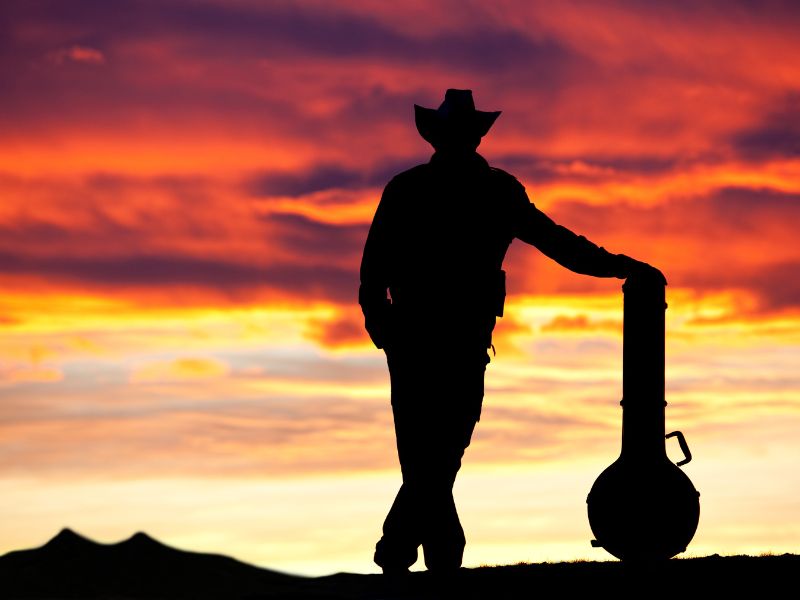 CO cechuje styl country? Na zdjęciu piosenkarz country na tle zachodu słońca.